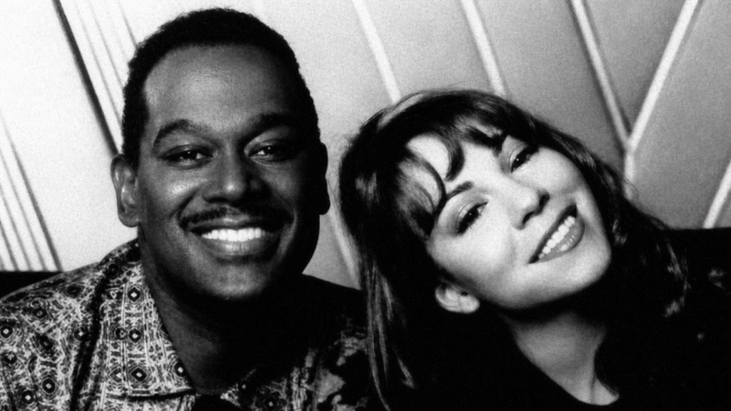 Luther Vandross and Mariah Carey smiling together in a restored black-and-white portrait